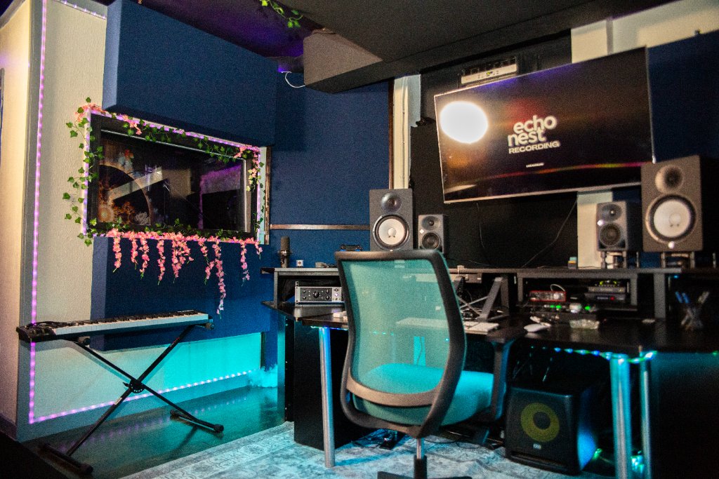 Control room with monitors and a keyboard, lit teal