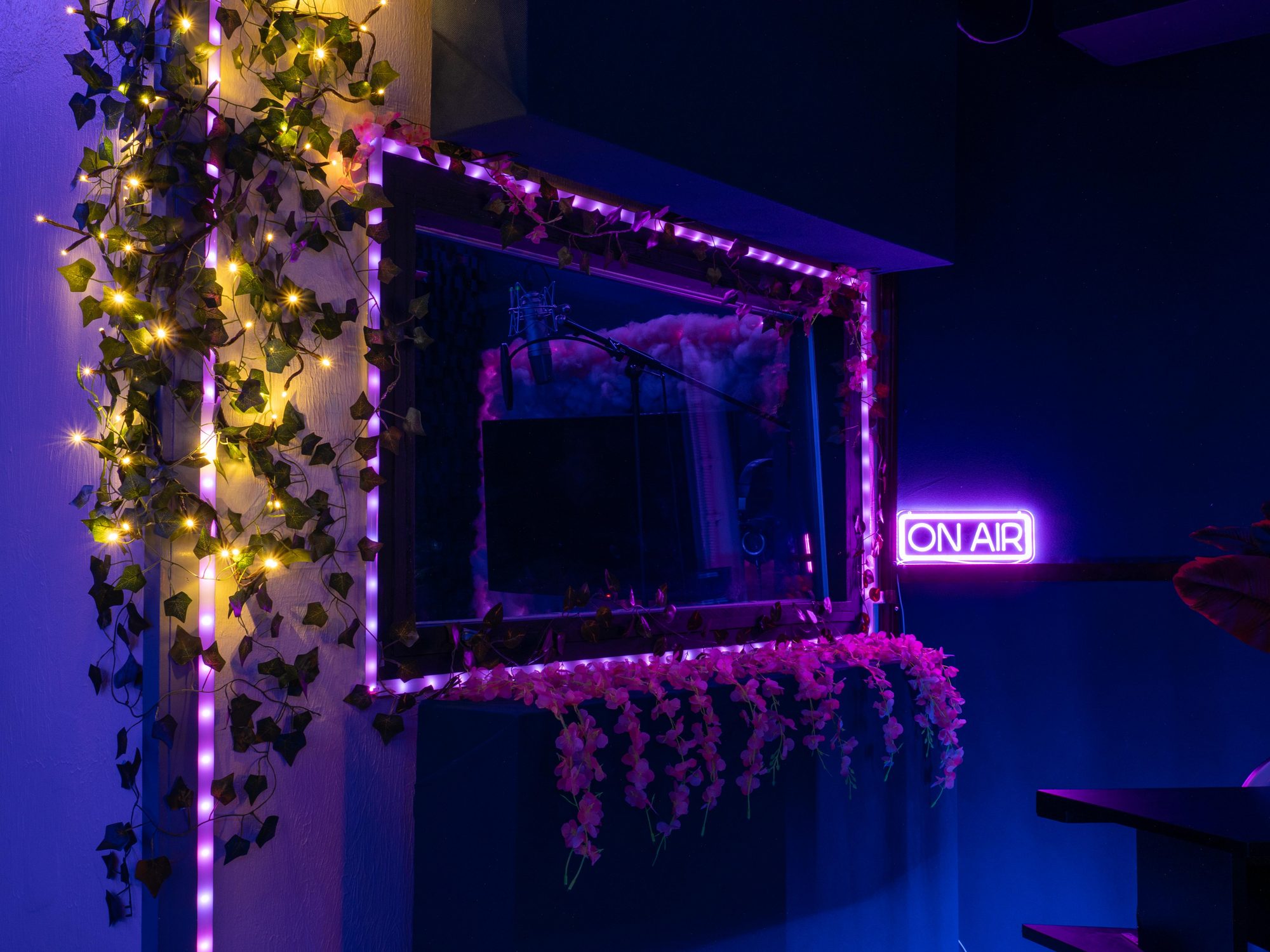 The booth window framed in string lights, ON AIR sign glowing beside it